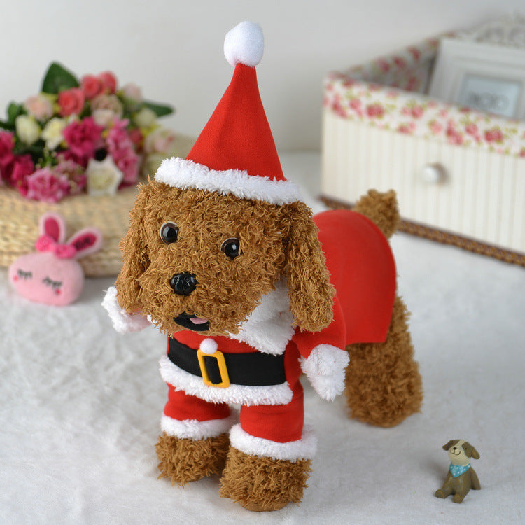 Plush toy dog in a Santa outfit on a light surface with flowers and a box in the background.