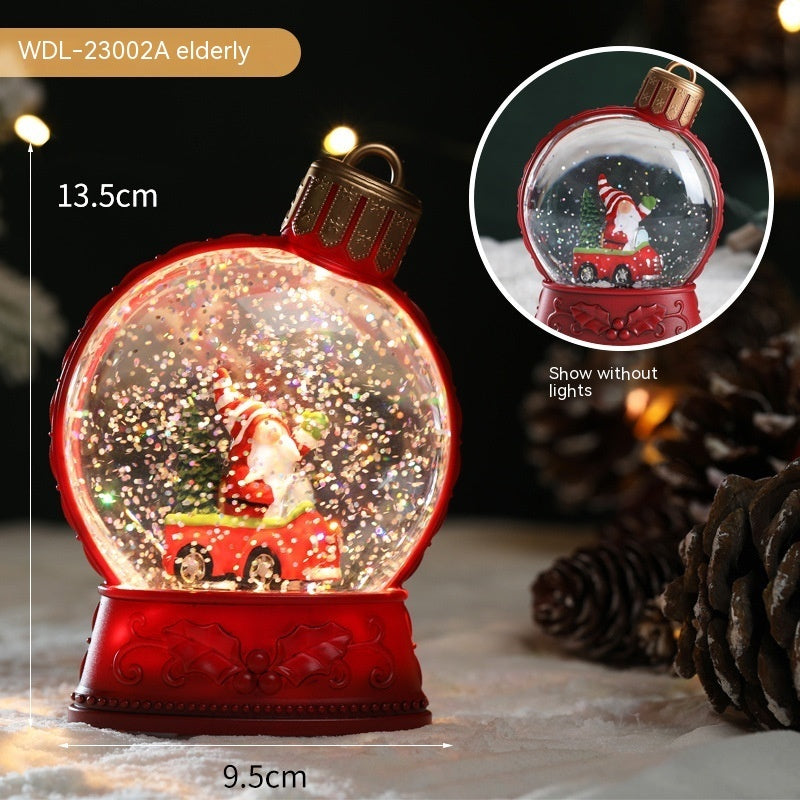 Red snow globe with Santa Claus and reindeer inside, surrounded by pine cones.