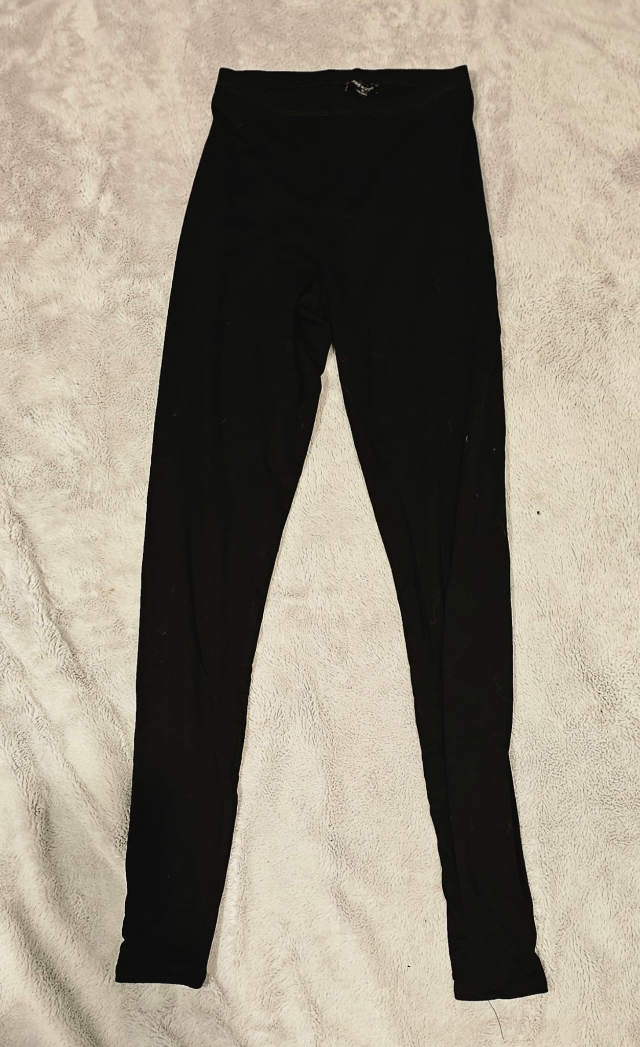 Black Naked Wardrobe leggings on a beige textured surface