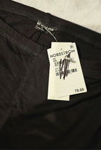 Black Naked Wardrobe pants with a Nordstrom tag on a textured surface