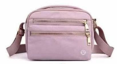Pink lululemon crossbody bag with gold zippers on a white background